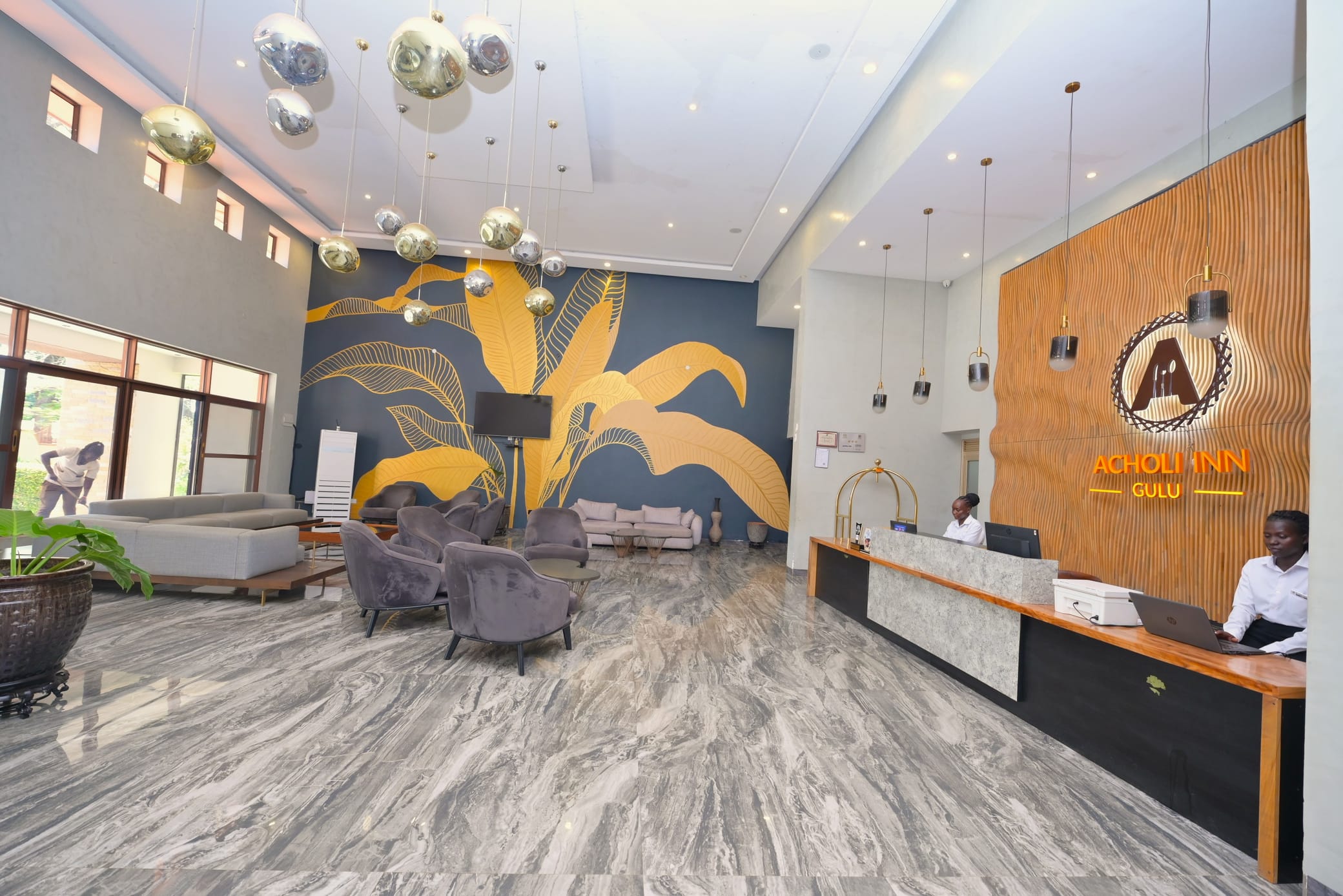 Acholi Inn lobby and reception with the illuminated logo and leaf mural