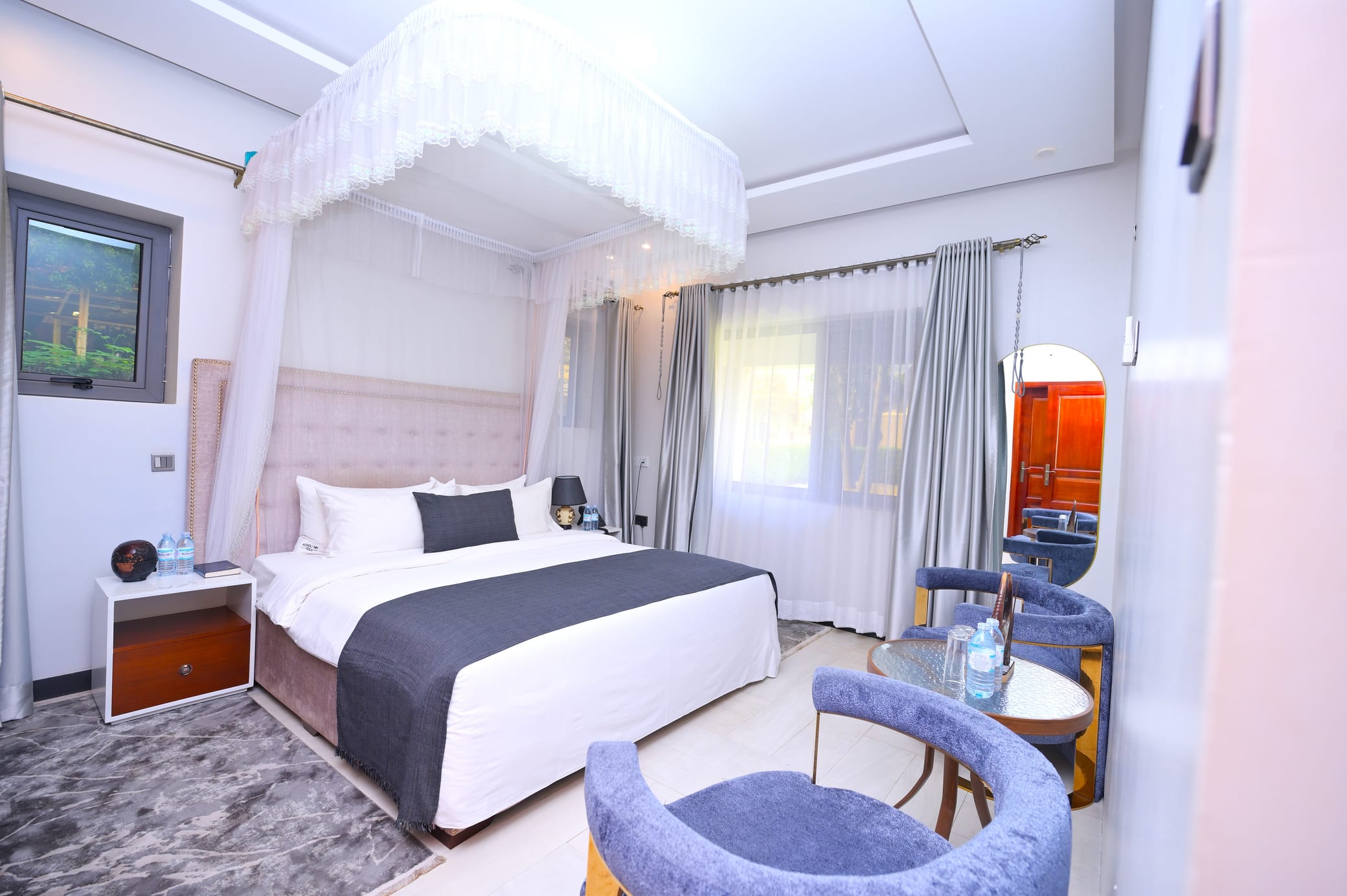 Acholi Suite with a canopied king bed and velvet lounge chairs