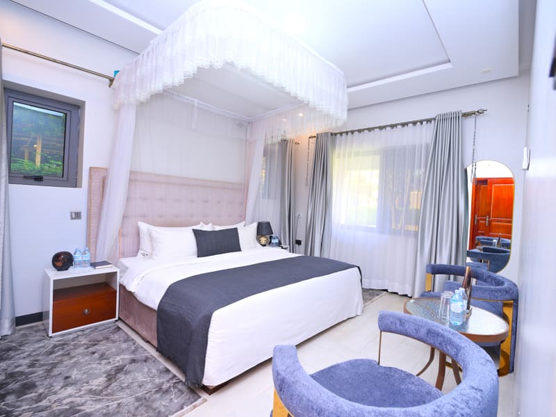 Acholi Suite with a canopied king bed and velvet lounge chairs