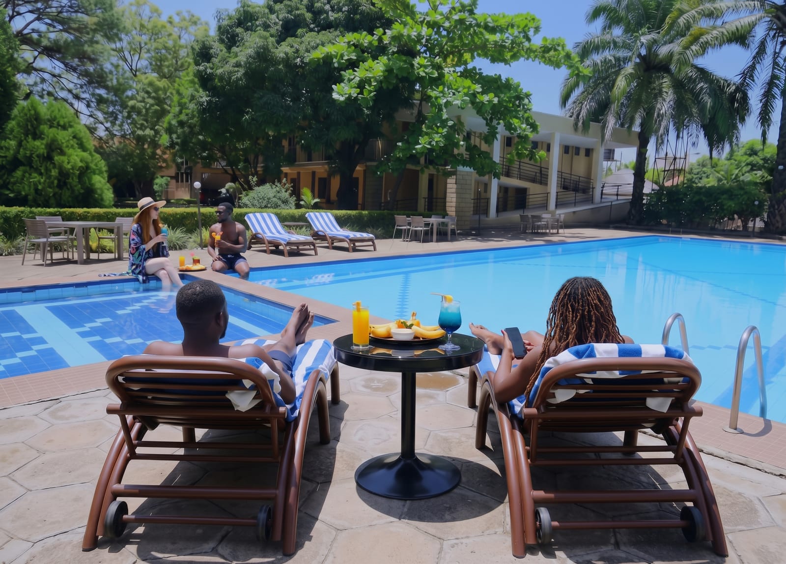 Guests relaxing on loungers with drinks and snacks beside the Acholi Inn pool